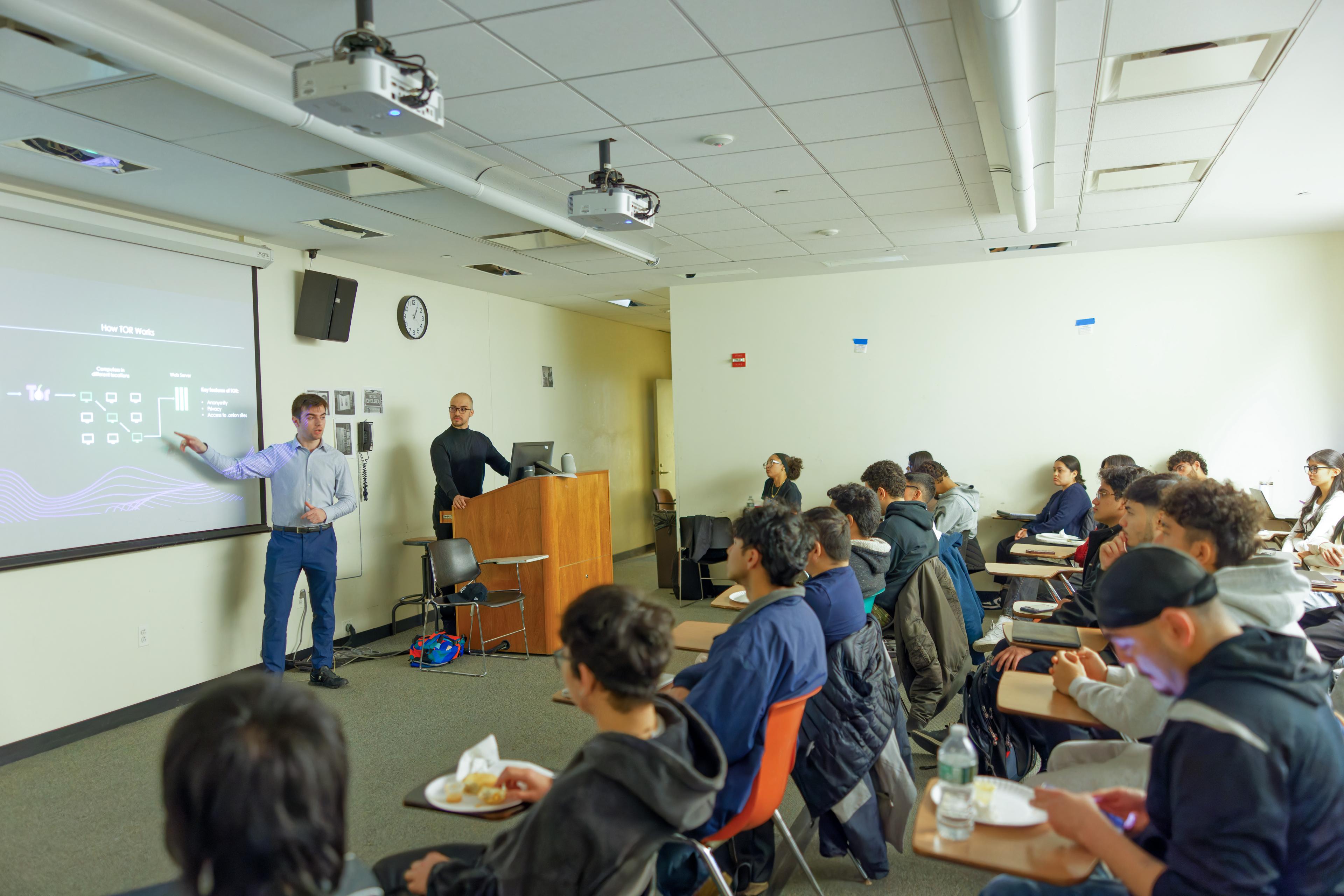 Two Cybersecurity Reach Foundation volunteers presenting to a room of university students