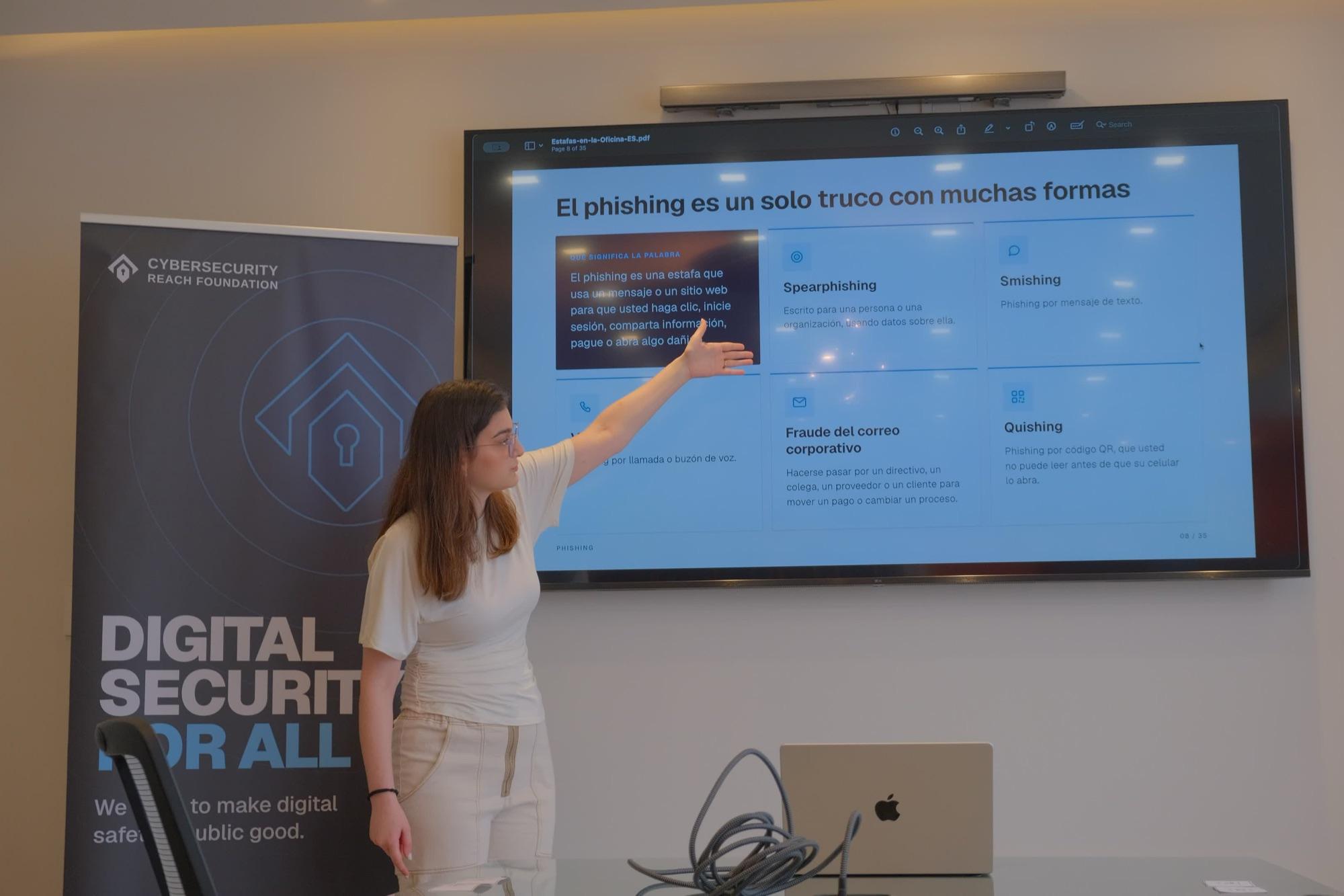 A volunteer presents a Spanish-language slide explaining the forms phishing takes, beside a Digital Security For All banner