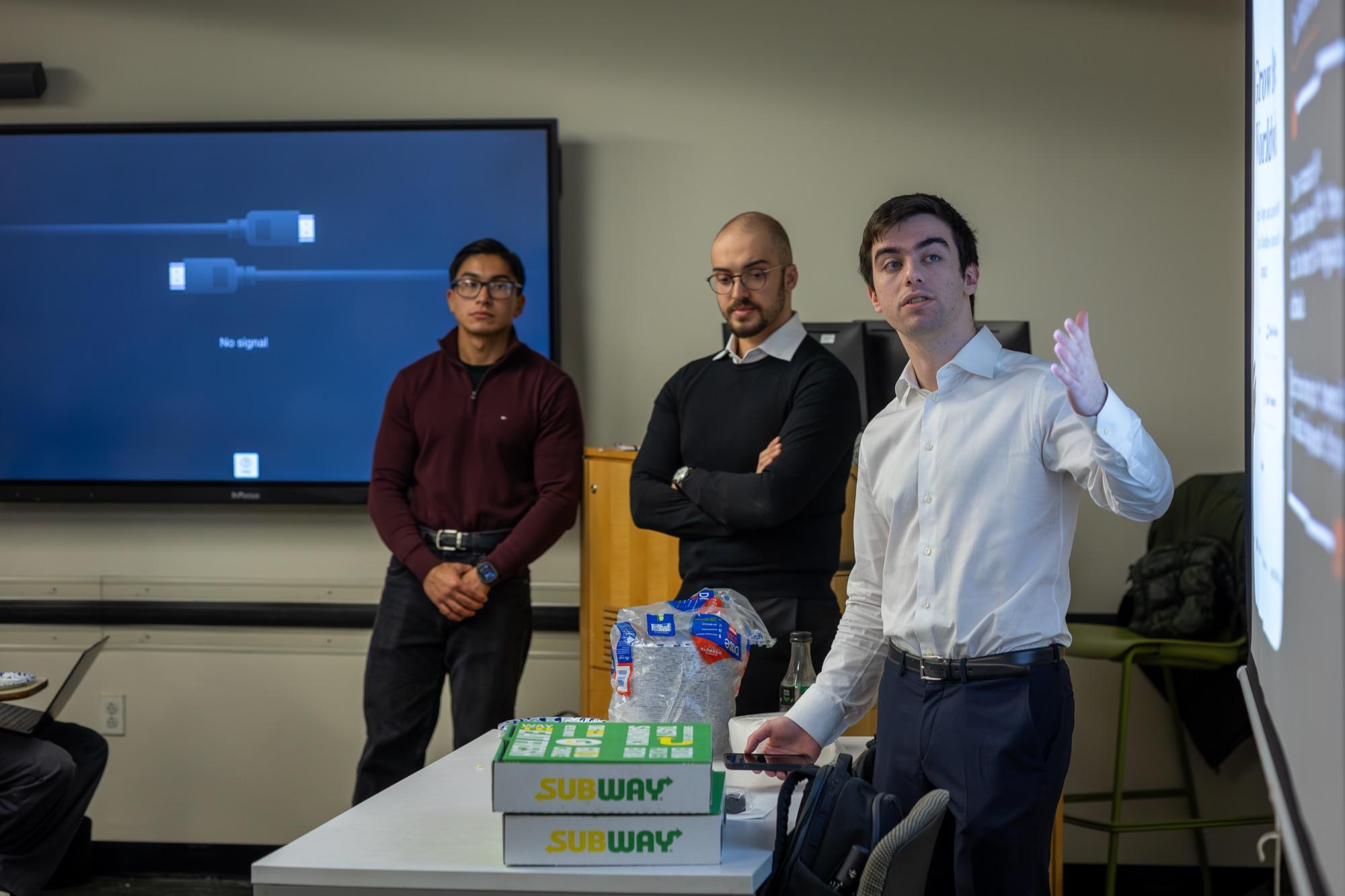 Three Cybersecurity Reach Foundation volunteers briefing a room at the start of a session